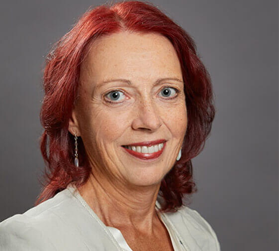 Headshot of Monique Porlier wearing a cream blouse with a flat grey background