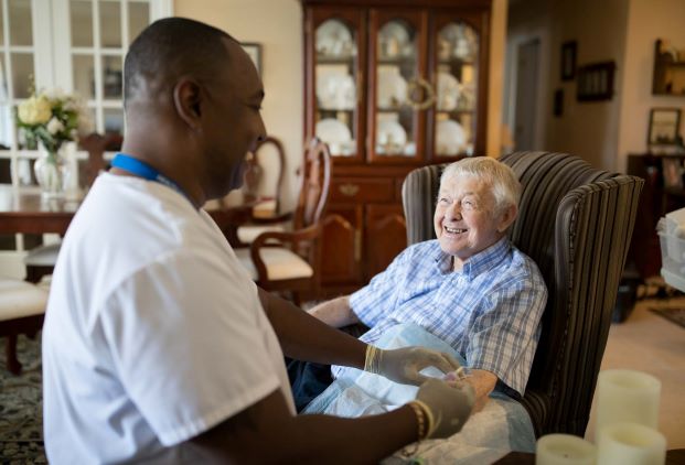 VON staff removing latex gloves standing next to seated client