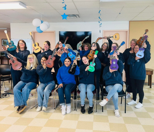 a large group of people holding up their ukuleles and smiling