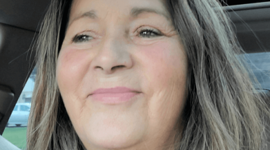 Photo of Ronda, hair down in the car, smiling