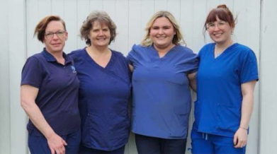 A photo of 4 PSWs standing and smiling in their blue attire