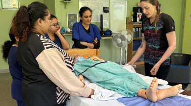 A group of students and an instructor grouped around a stretcher with a manikin